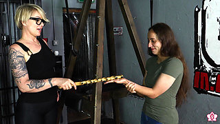 Slave Mila's Feet Dangle and Quiver as Mistress Baton Breaks in Heavy Wooden Paddle Over Her Jeans and Bare